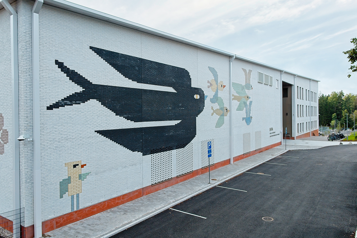 Rakennuksen tiiliverhoiluun on toteutettu taidetta, jossa on kuva isosta mustasta linnusta ja pienemmistä vaaleansävyisistä linnuista.